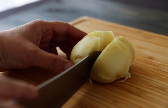 蒸し上がったじゃがいもを包丁で４等分にカット